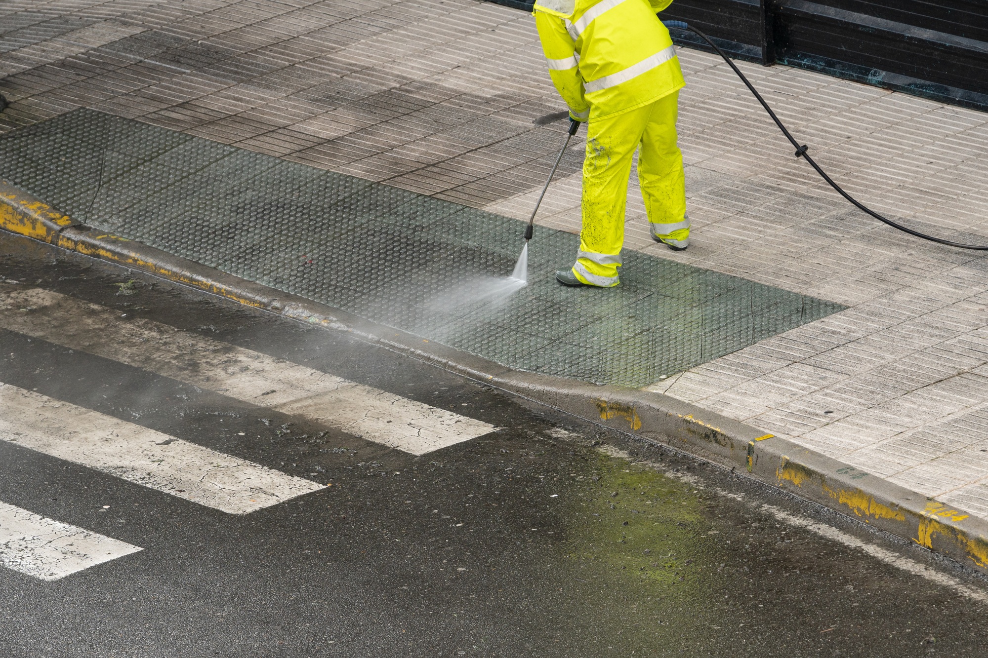 Sweeper cleaning a street sidewalk with high pressure water jet